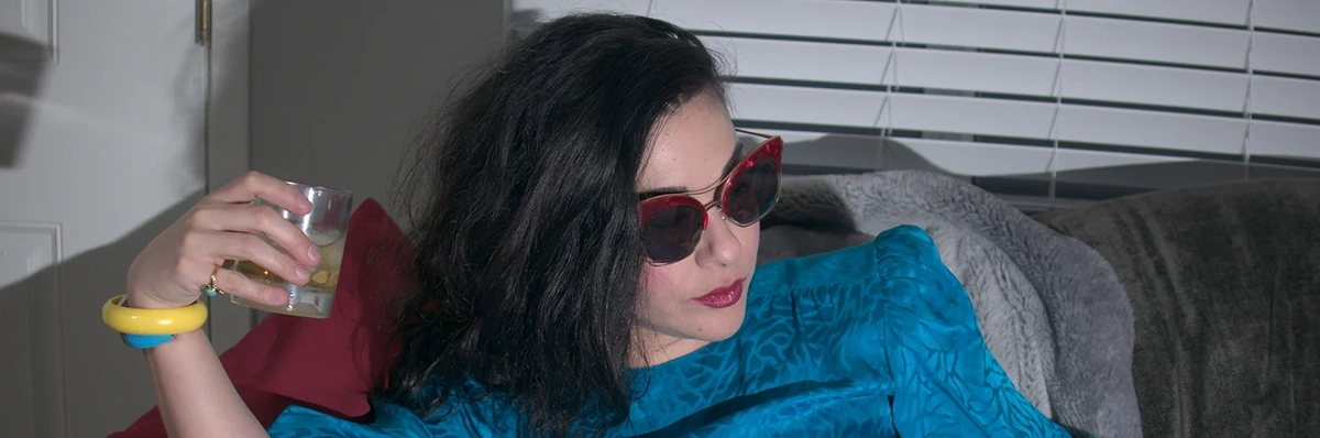 Marcelina Chavira reclining with sunglasses and a cocktail